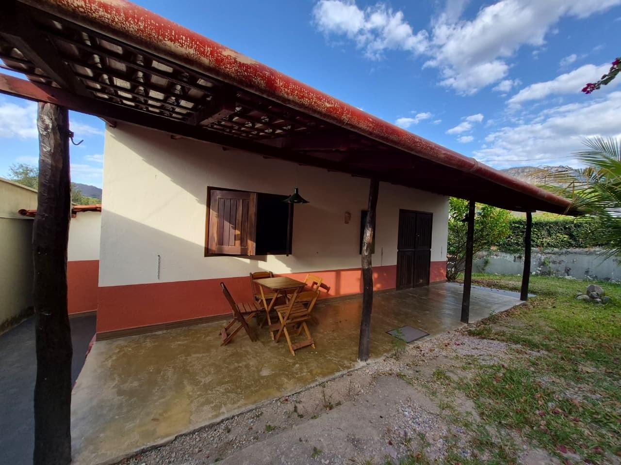 Varanda da frente da casa, com mesa, cadeiras e vista para a serra
