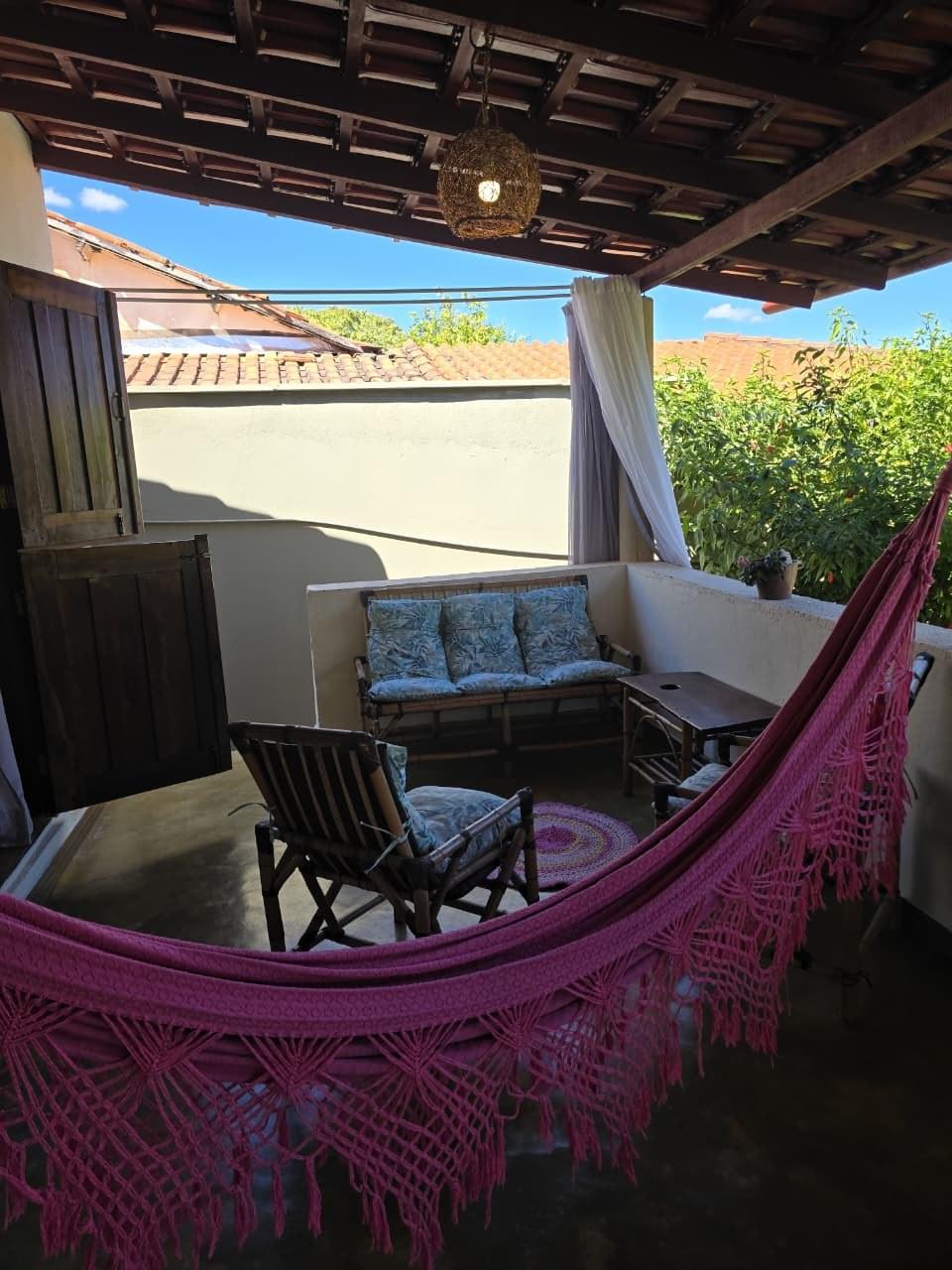 Varanda com sofás de vime e rede rosa