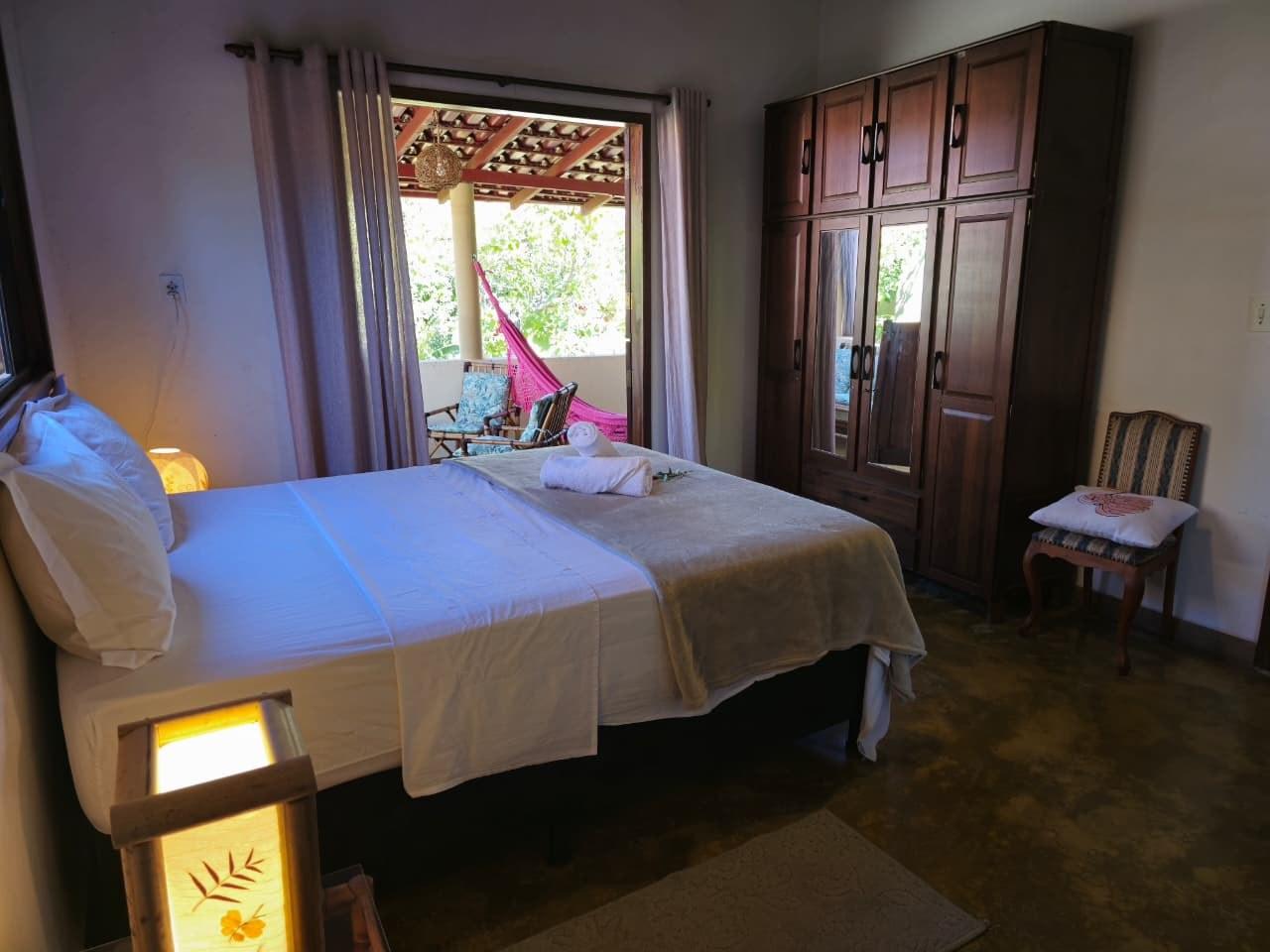 Suíte da Casa da Artista, com cama de casal e porta para a varanda com rede