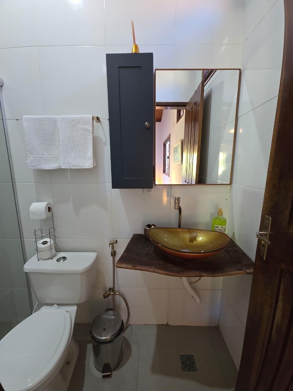 Pia dourada do banheiro, com espelho refletindo o corredor