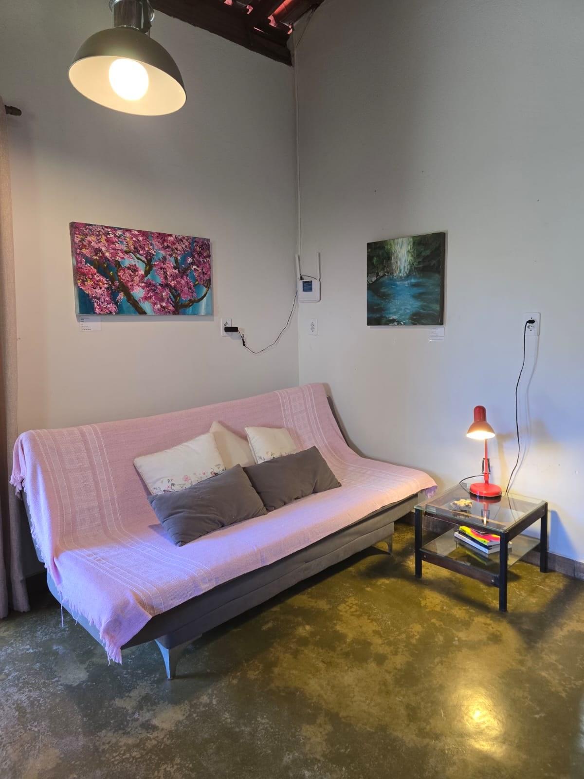 Sala de estar da Casa da Artista, com sofá rosa e pinturas na parede